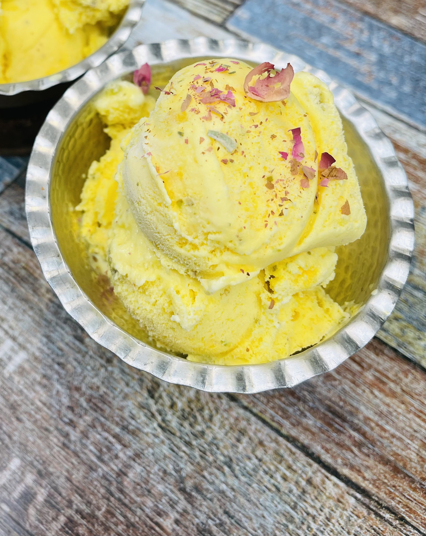 Persian saffron ice cream in a hammered-silver bowl with rose petals and slivered pistachio